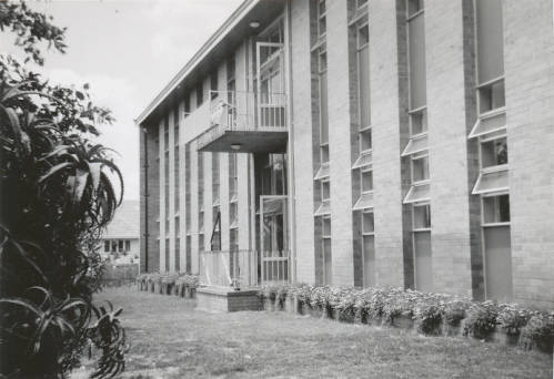 Parnell House - St Hilda's Anglican School For Girls Black-and-white photo of a brick school building with tall windows, a central entrance with a staircase, and a lawn with shrubs.