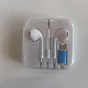 Open white earbud charging case showing two white earbuds with a central inline remote; a blue USB drive is visible at the right edge.
