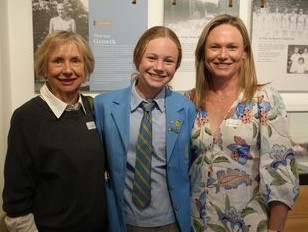 f_2_34489988 - St Hilda's Anglican School For Girls Three smiling people posing for a photo: a student in a blue blazer and striped tie between two adults, in a school hallway with displays in the background.